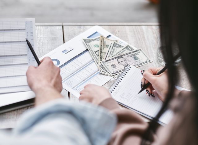 Two people working on financial documents and dollar bills
