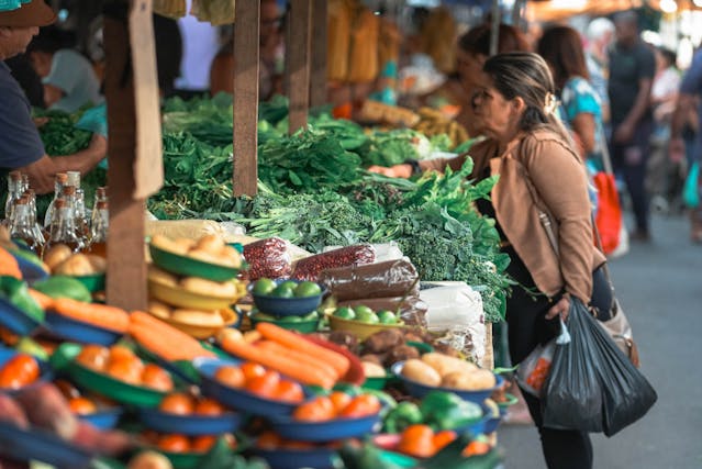 person in front of vegetable stand at street market