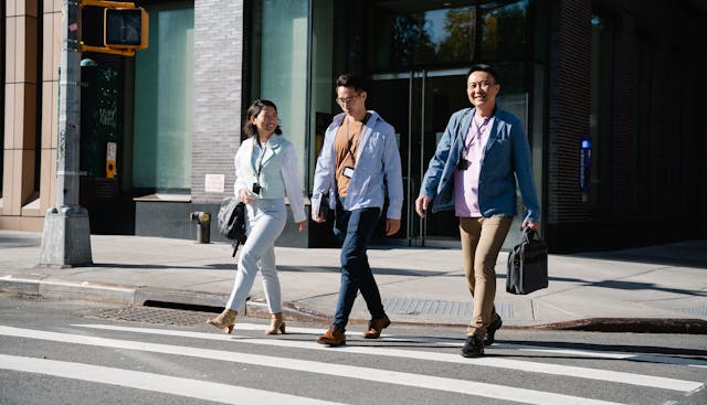 Three People Smiling While Crossing the Street