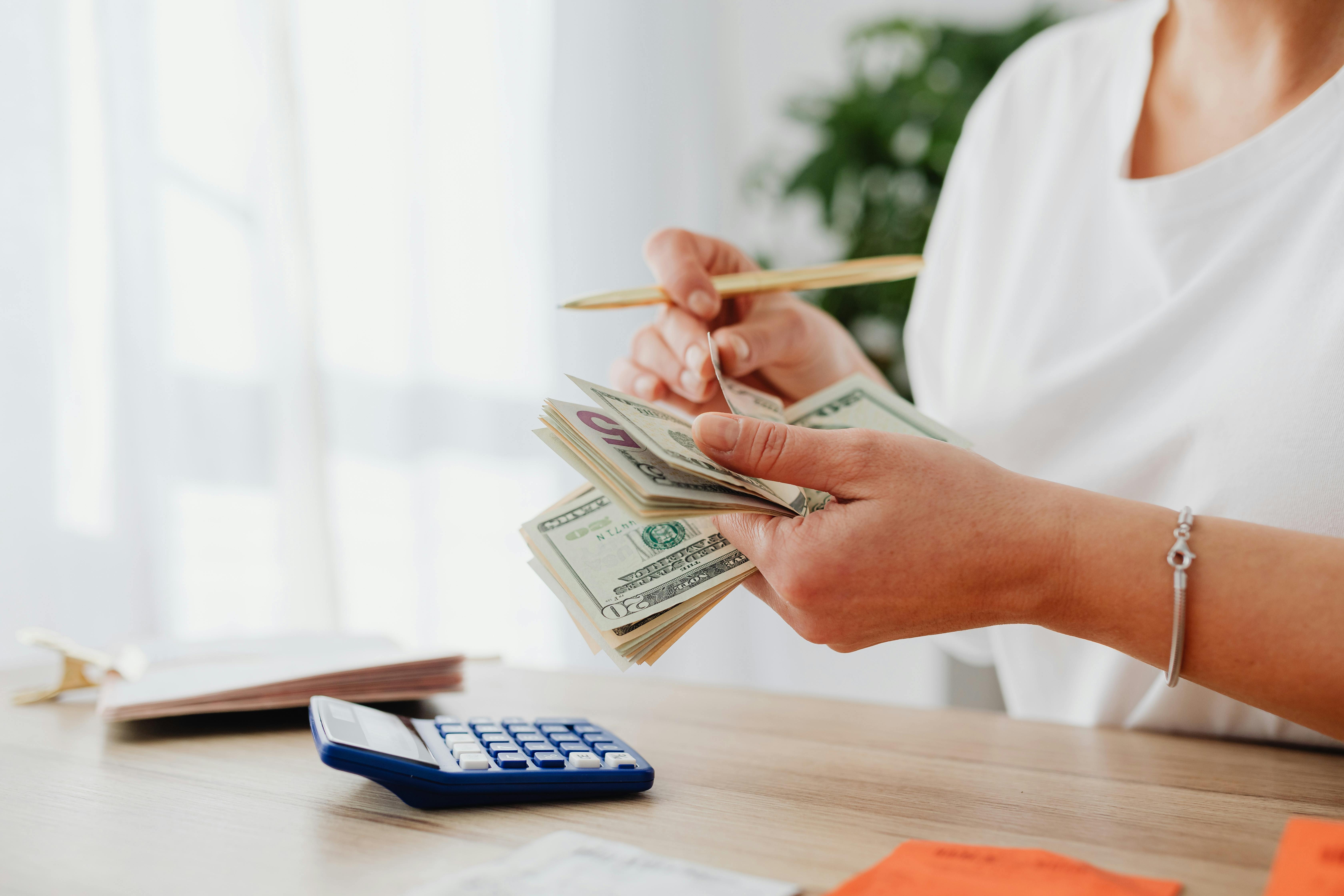 someone counting cash with a calculator in front of them