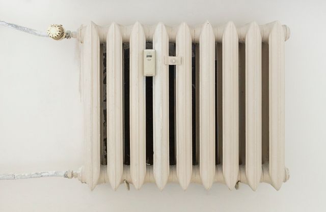 A classic white metal radiator on a plain wall