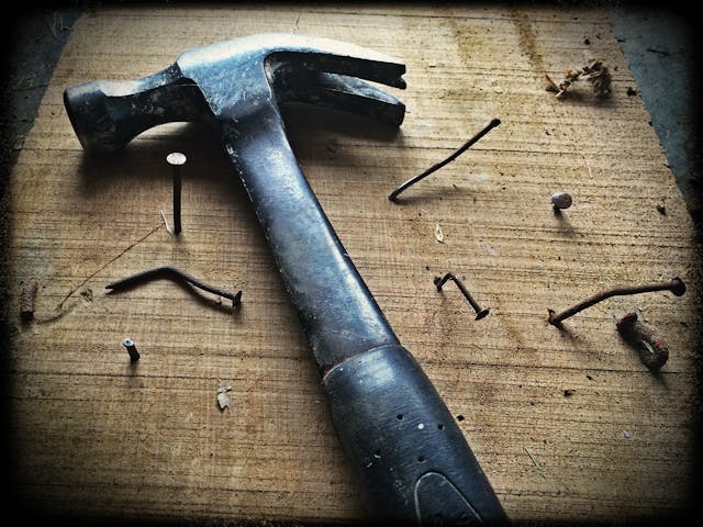 black-hammer-and-nails-on-wooden-plank