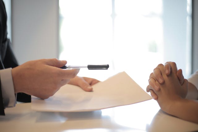 someone handing over a pen and paper