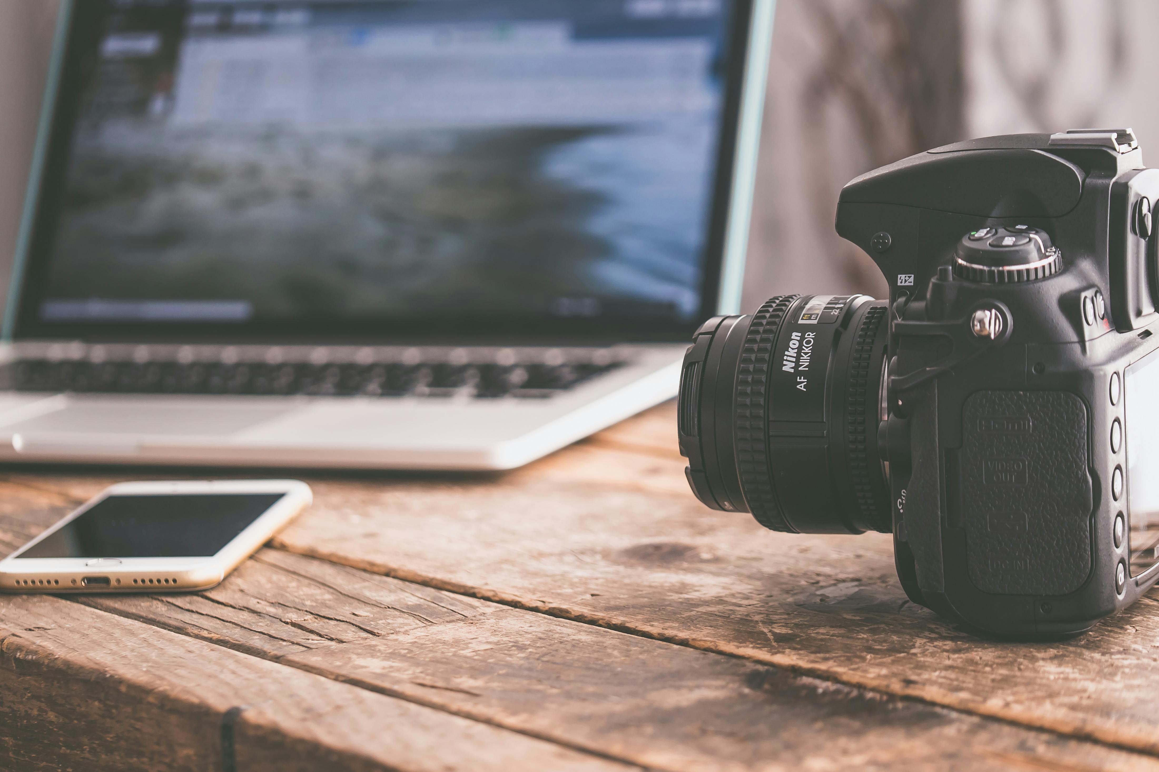 a camera next to a phone and open laptop