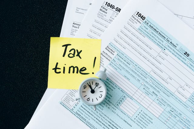 tax documents on a black table with a sticky note that says tax time